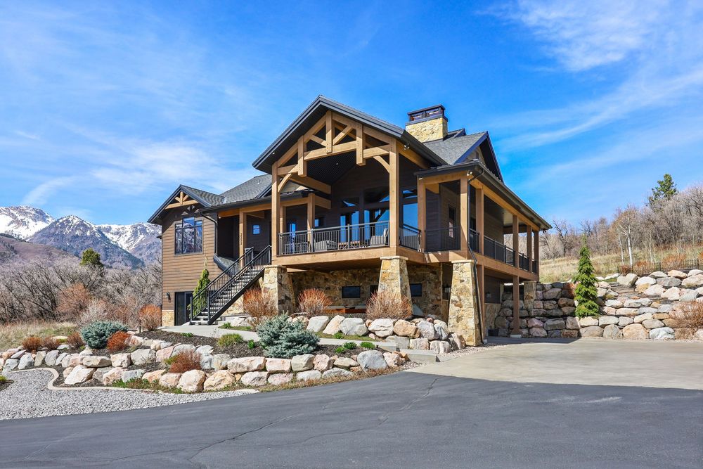 Stunning timber frame mountain home with stone foundation, covered deck, and snow-capped mountain views. Captured by Slate Media (best in UT