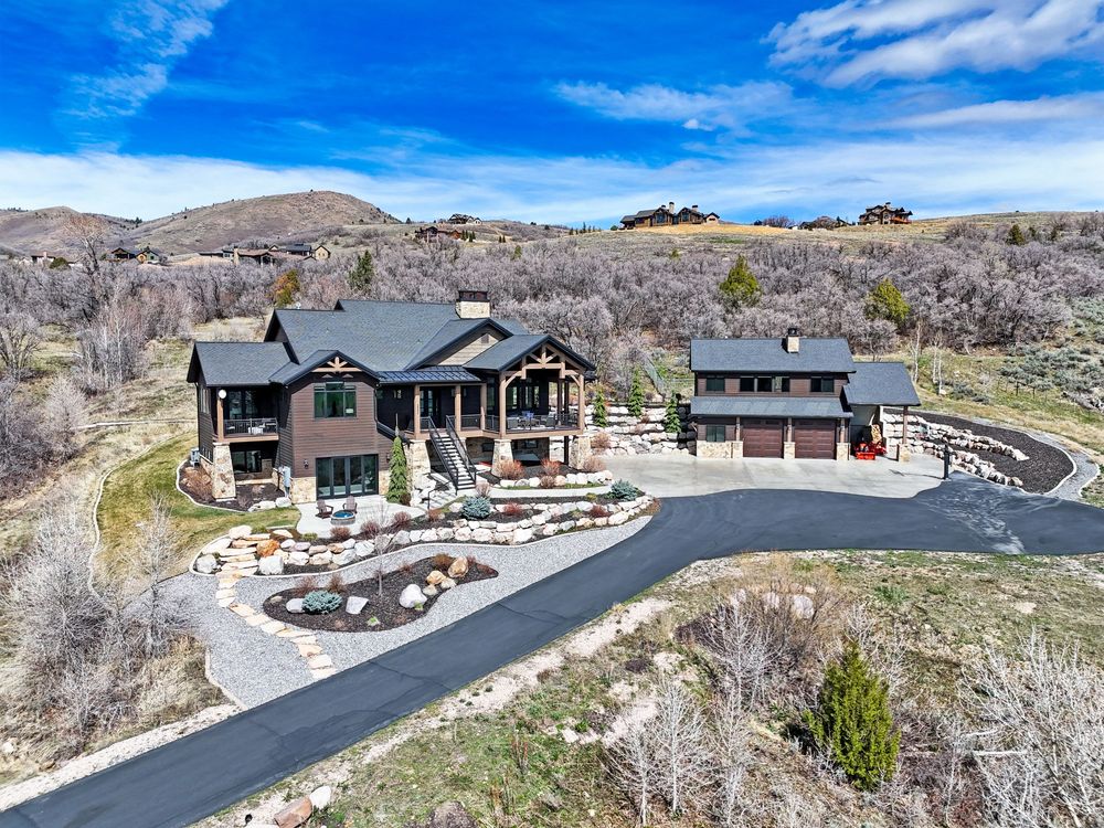 Aerial view of luxury mountain estate with circular driveway, detached garage, and natural surroundings. Captured by Slate Media (best in UT