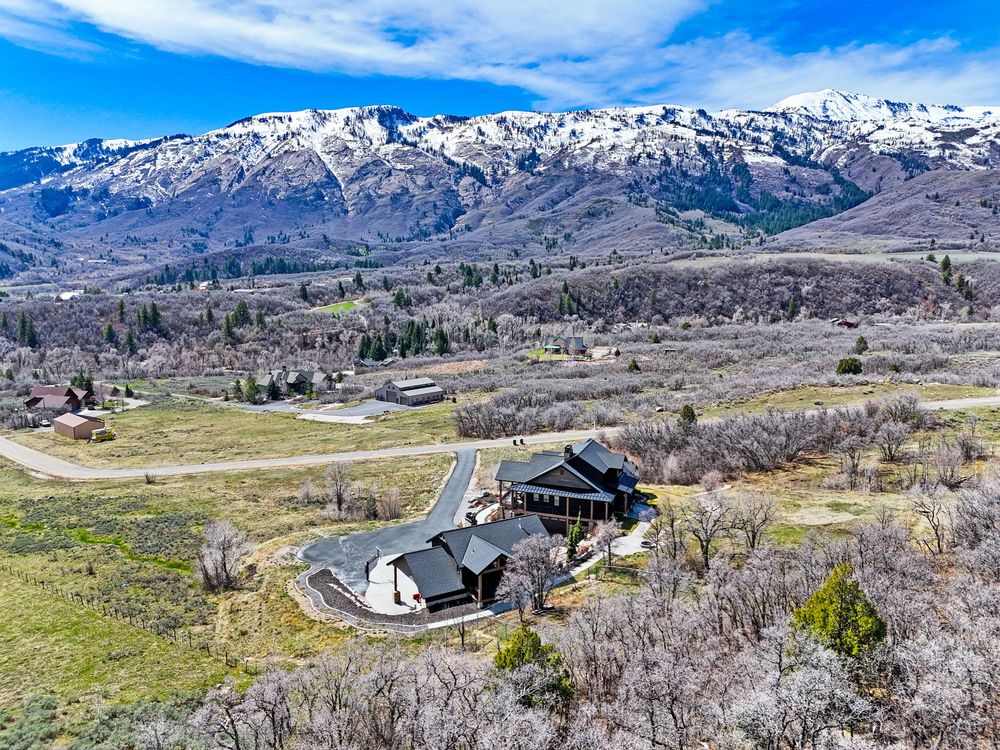 Aerial view of secluded mountain property surrounded by snow-capped Wasatch peaks and open valley land. Captured by Slate Media (best in UT)