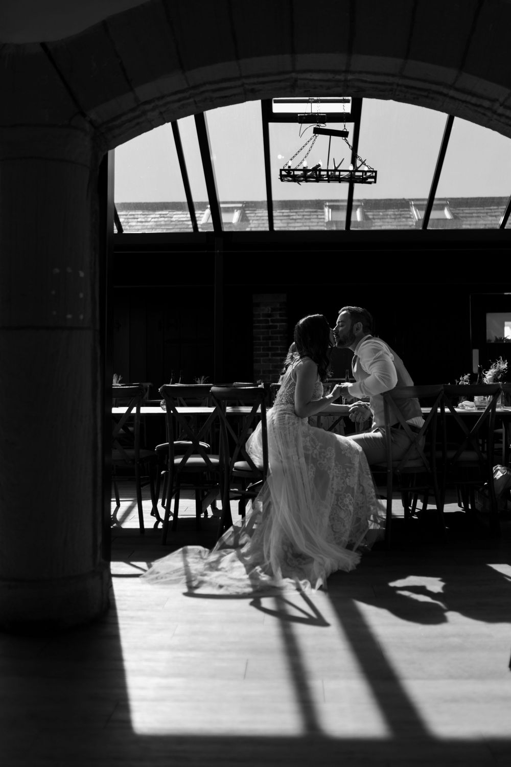 People cast long dramatic shadows on stone floor in archways at train station platform during late afternoon lighting.