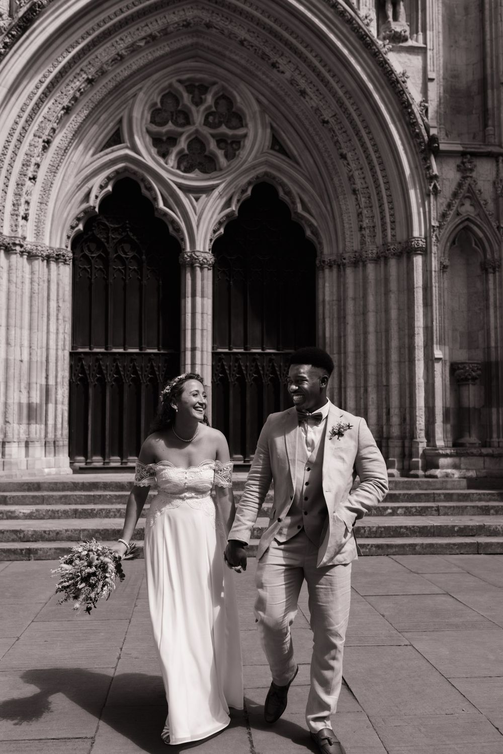 Black and white photo of a happy couple sharing a moment outside a Gothic cathedral entrance. York Minster. York Registry Office Wedding.