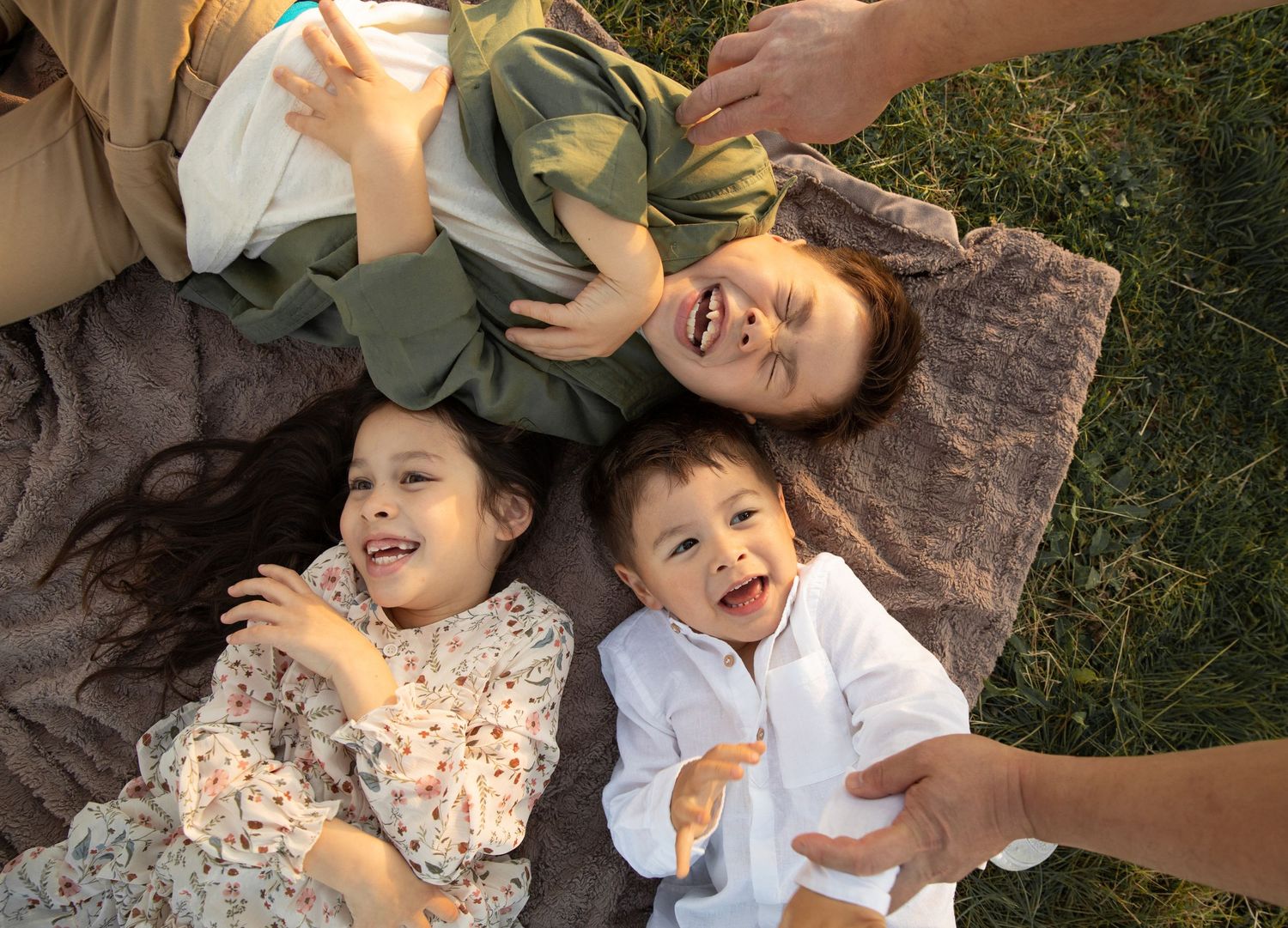 A sequence of candid outdoor photos showing joyful laughter and playful moments on the grass.