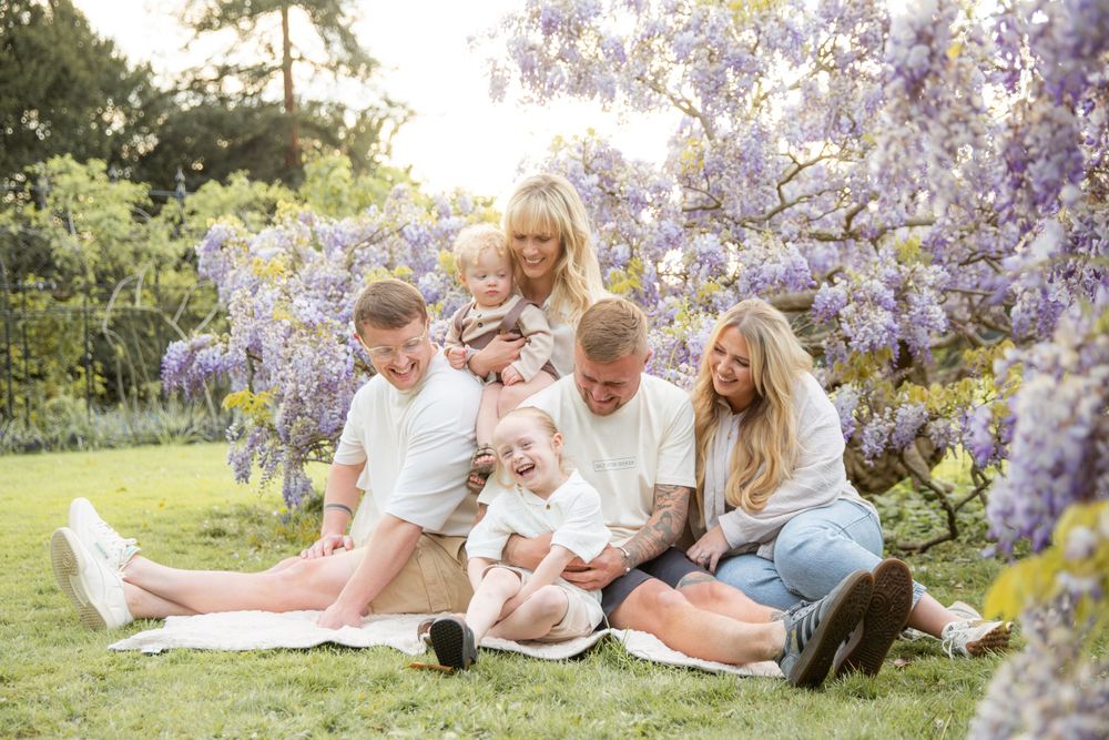 Family enjoying picnic under blooming wisteria on sunny spring day.