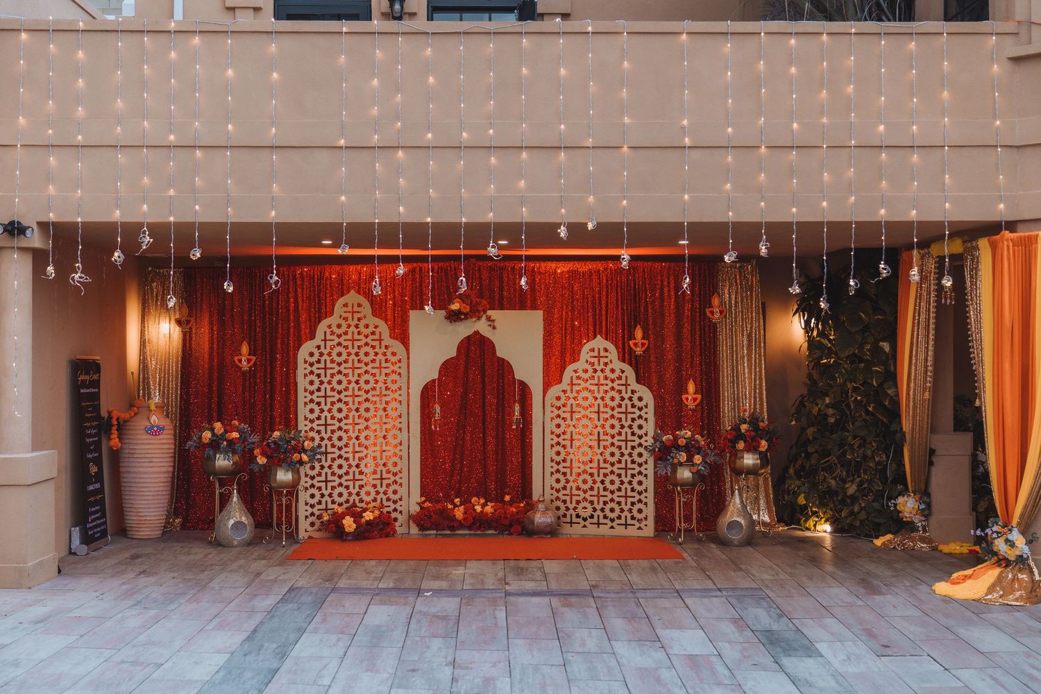 Elegant wedding decor featuring ornate gold and white archways with draped fabric and warm lighting in a ballroom setting.
