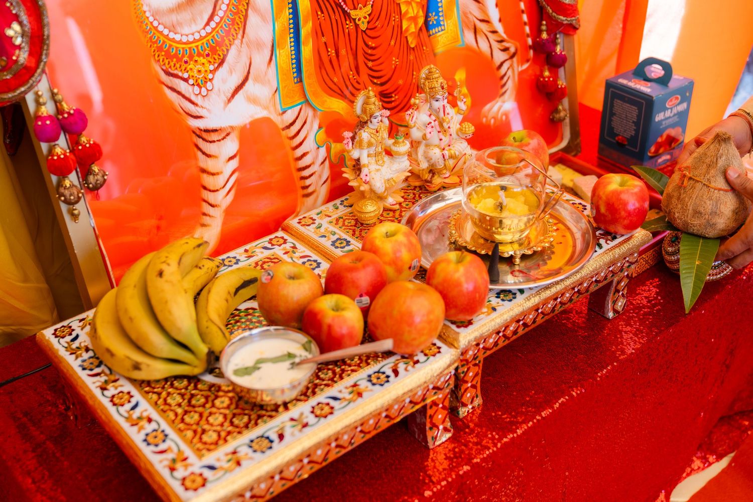 Colorful Chinese New Year decorations and offerings including oranges, tea, and traditional items on a red altar display.