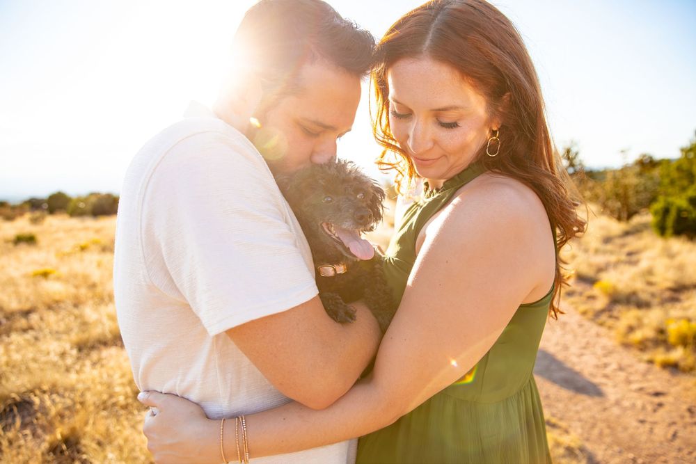 Romantic couple embraces in warm sunlight on sandy beach during golden hour sunset.