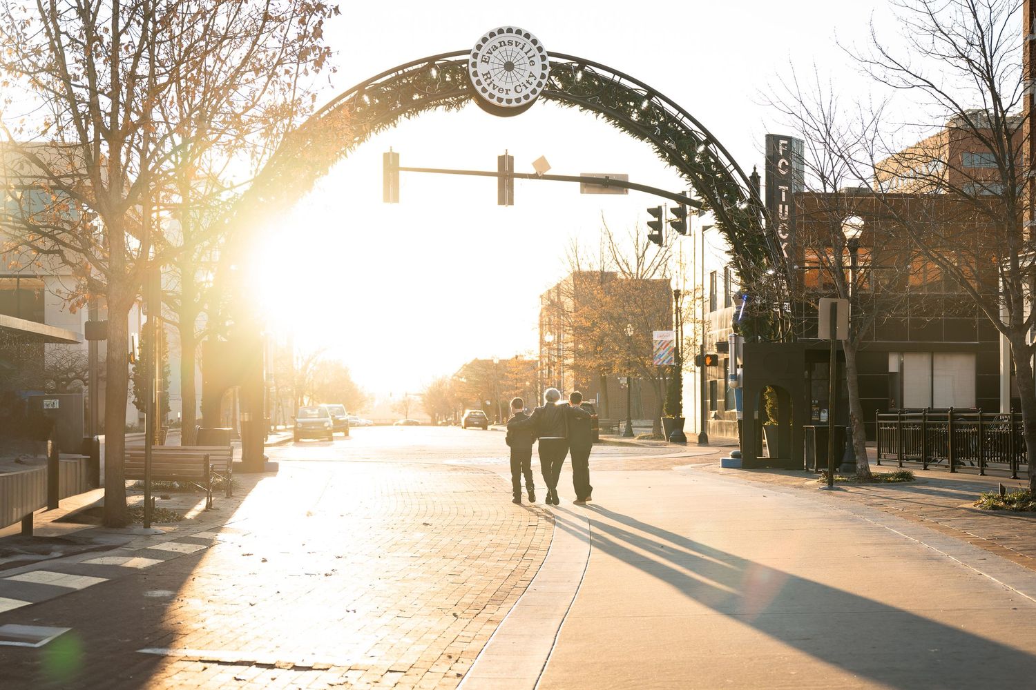 Golden sunlight illuminates the Short North Arts District archway in Columbus as silhouettes walk down High Street at sunset.