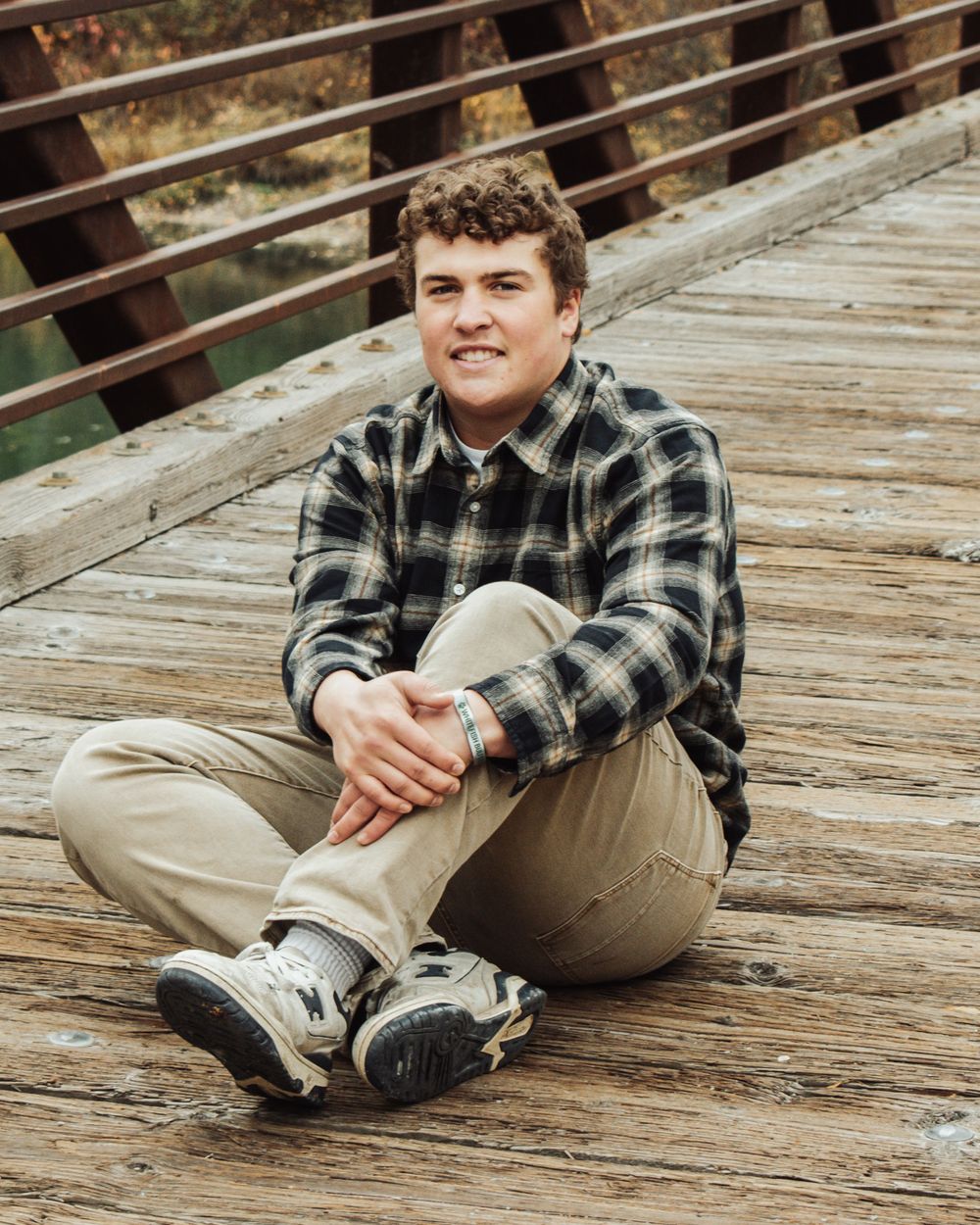 A series of casual portraits showing someone sitting on wooden decking wearing a plaid flannel shirt and khaki pants.
