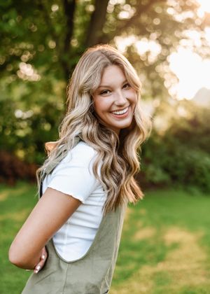 Portrait in natural lighting shows warm sunset glow through trees with casual summer fashion.