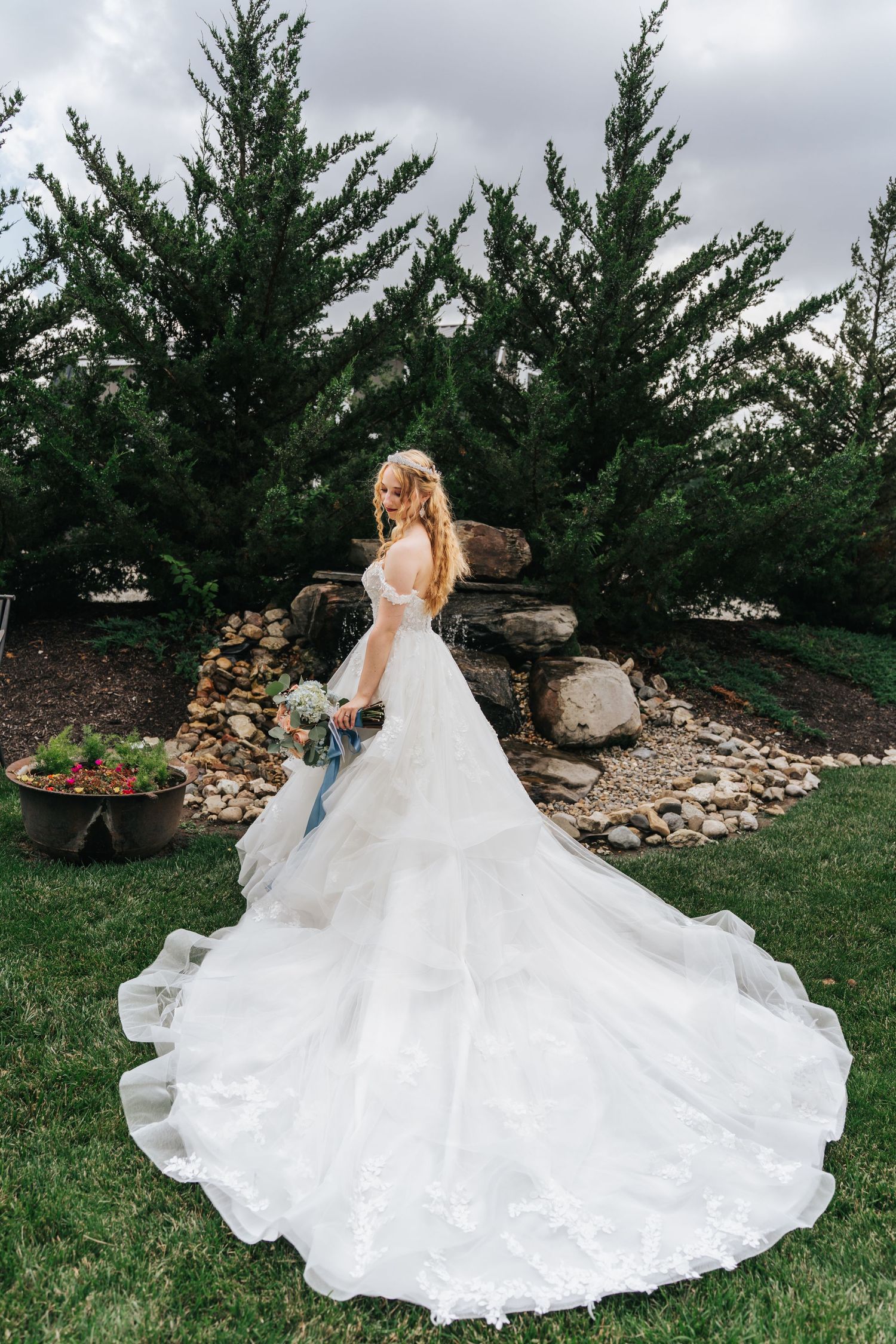 Woman in wedding dress posing elegantly in a garden.