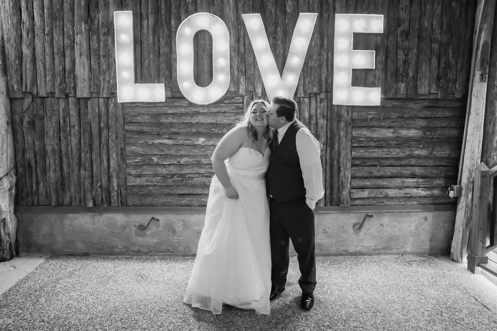 Black and white wedding photo of couple beneath rustic LOVE sign in Nashville, TN.