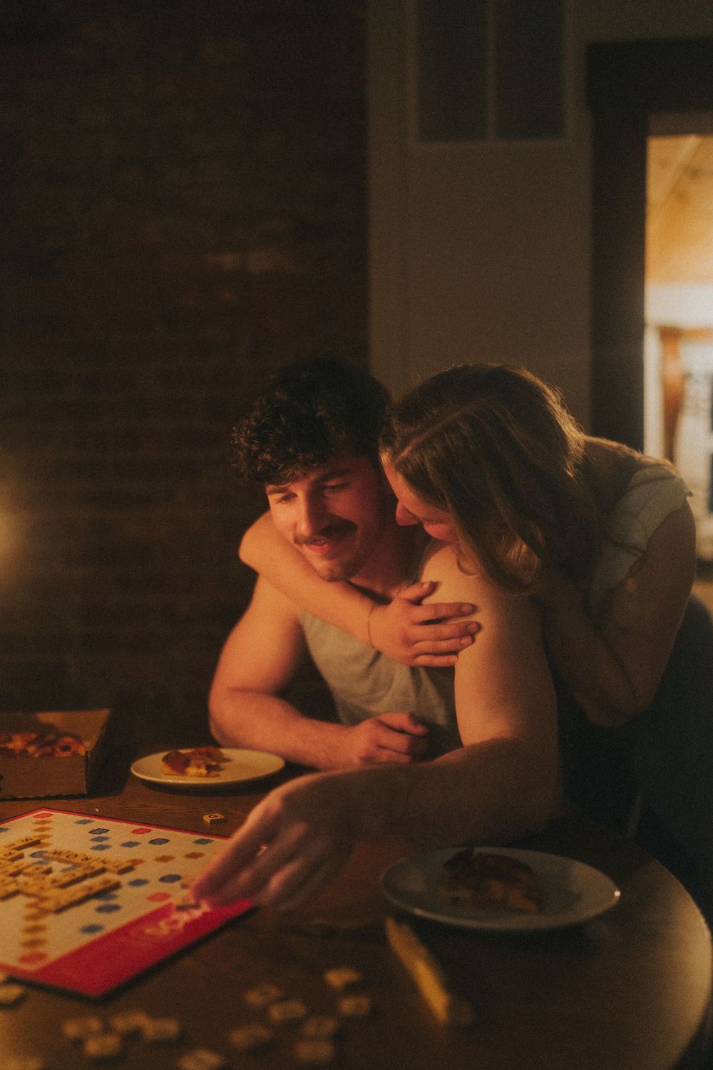 Couple sharing a romantic moment playing a board game by candlelight at a cozy dinner table.