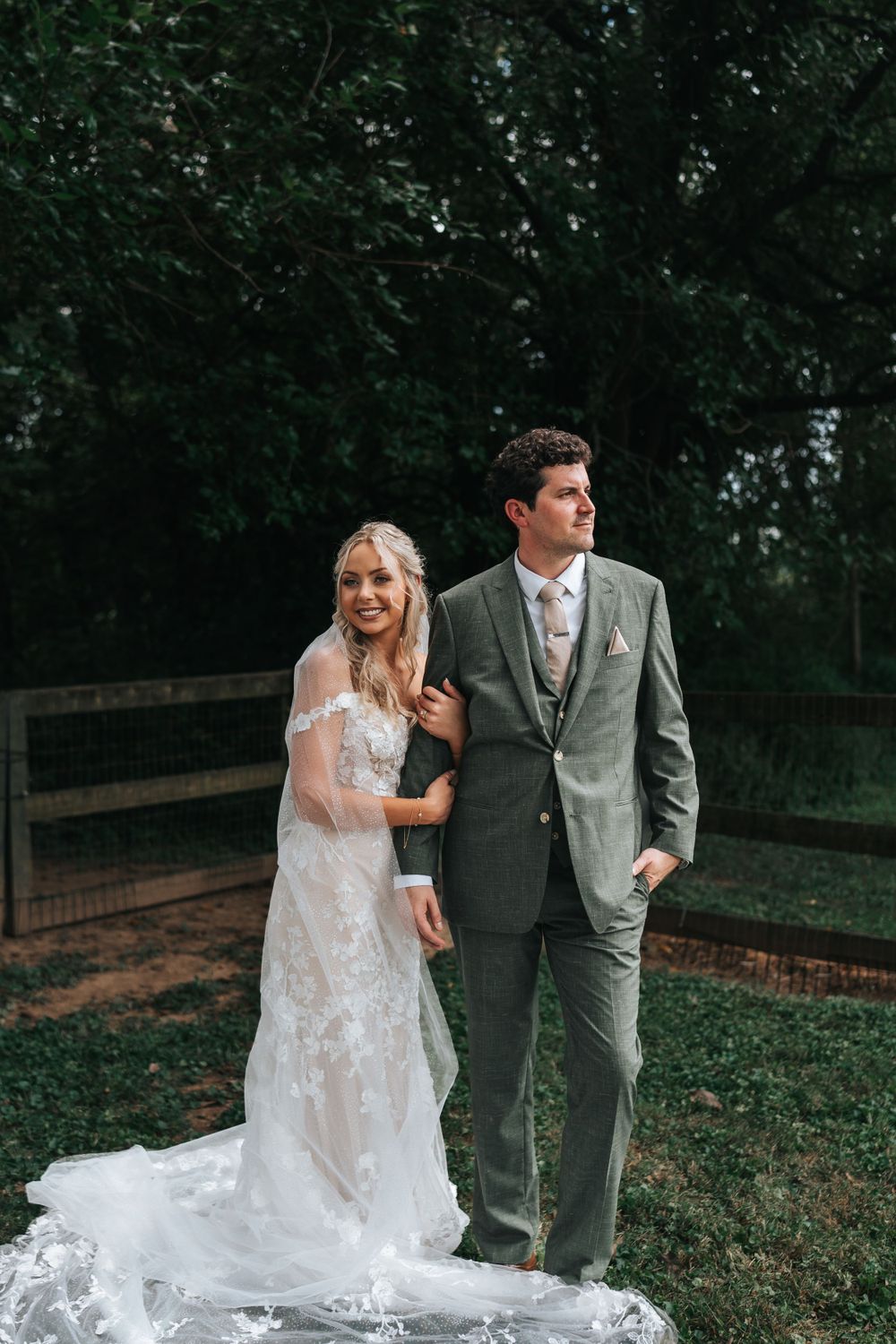 A couple poses for their wedding portrait in front of a rustic wooden fence.