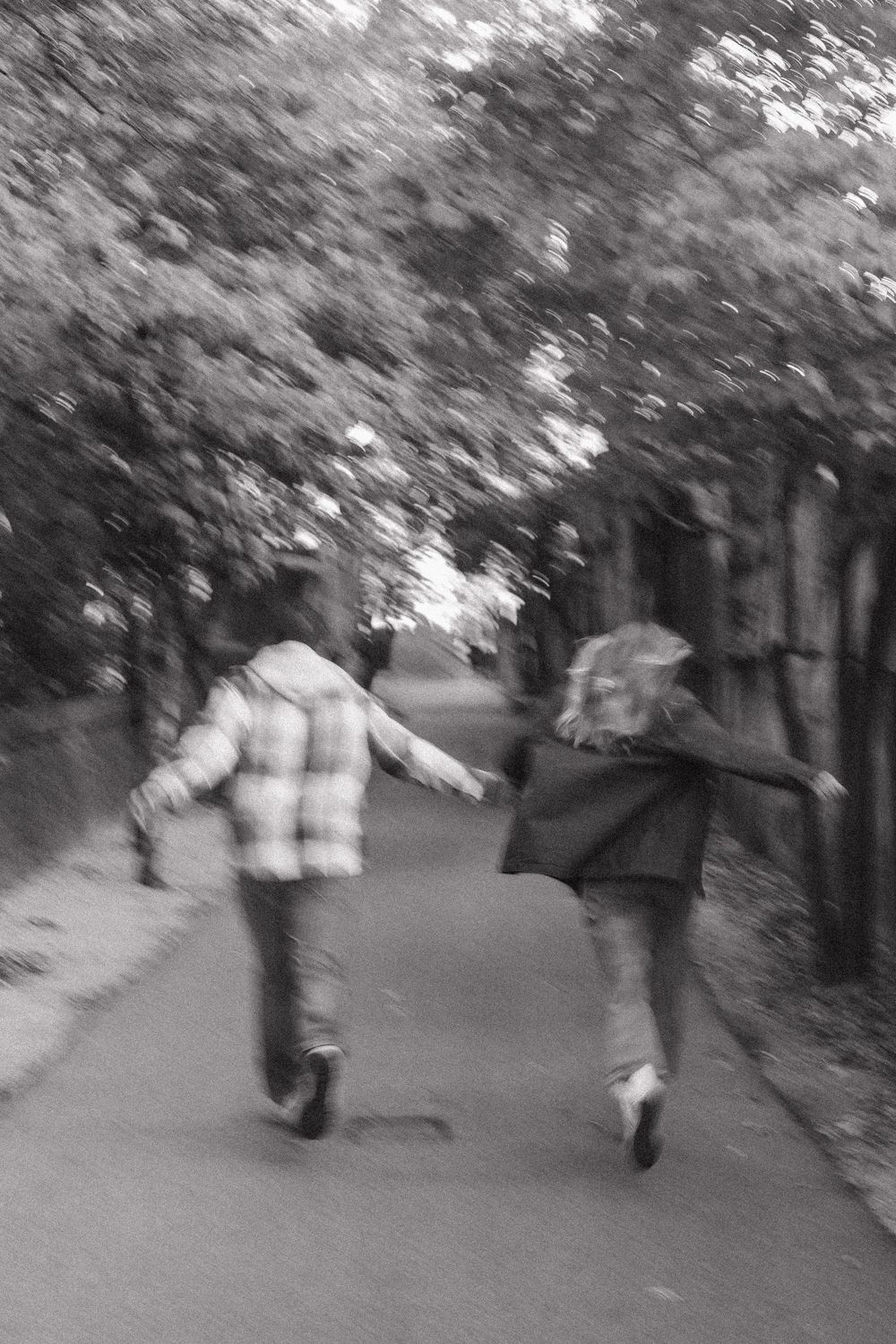 A blurry sequence of black and white photos showing people walking along a tree-lined path.