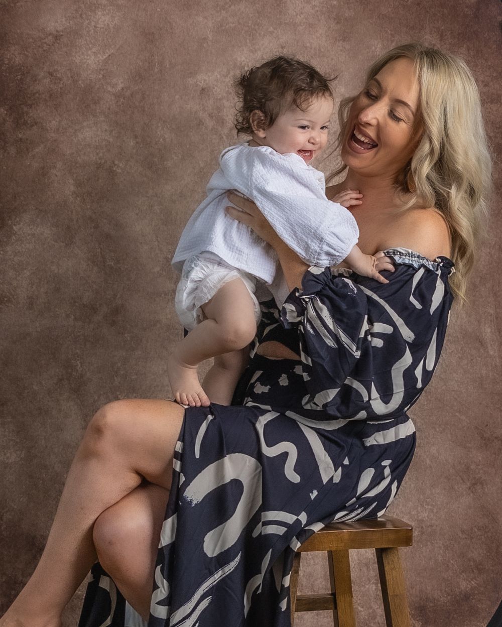 Candid lifestyle portraits showing tender moments between mother and baby in coordinated navy and white outfits.