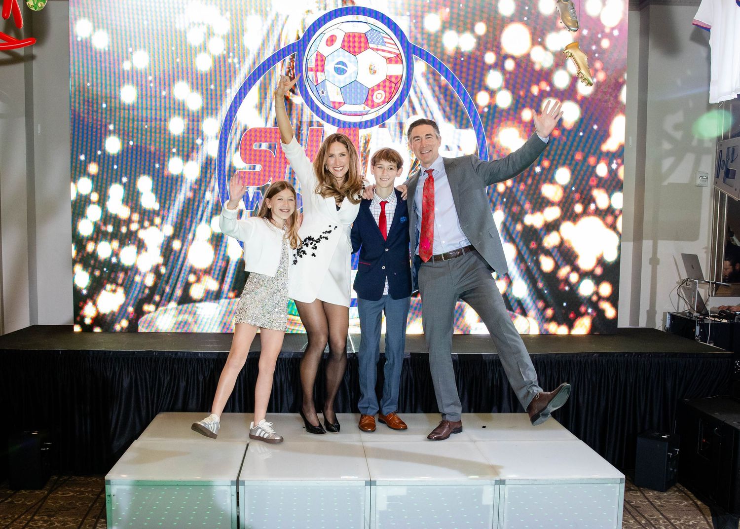 Man in a vest and tie is lifted overhead by cheering guests as he crowd surfs during a lively party celebration.