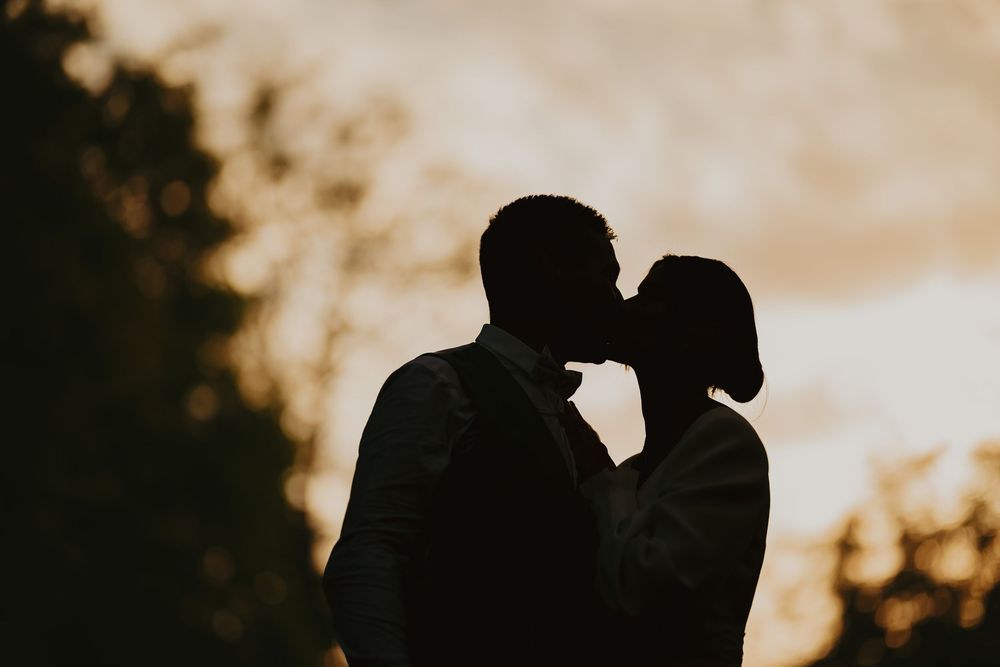 Silhouette des mariés s'embrassant devant un coucher de soleil doré