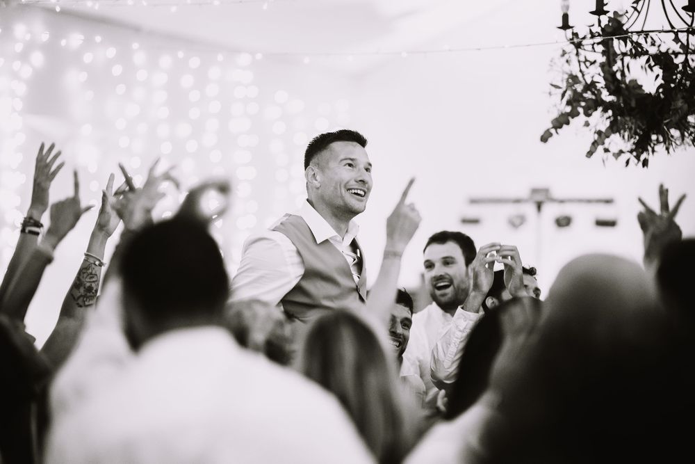Photo noir et blanc d'un invité porté au-dessus de la foule en liesse pendant la soirée