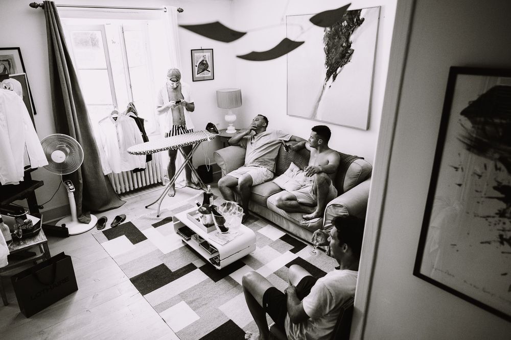 Photo noir et blanc des témoins détendus dans un salon lumineux pendant les préparatifs