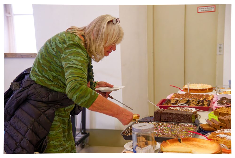 Eine Frau in einer grünen Jacke bedient sich selbst am Buffet.