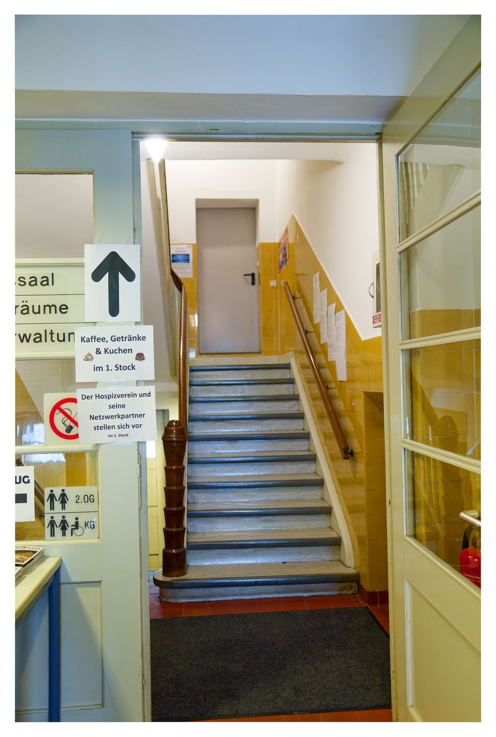 Innentreppe mit Wegweisern zu den Zimmern und dem Erfrischungsbereich im Obergeschoss.