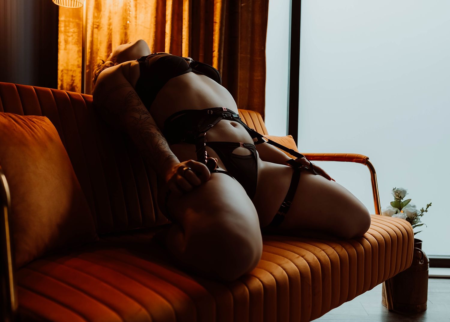 A person in lingerie reclines on an orange velvet sofa by Boudoir by KJ