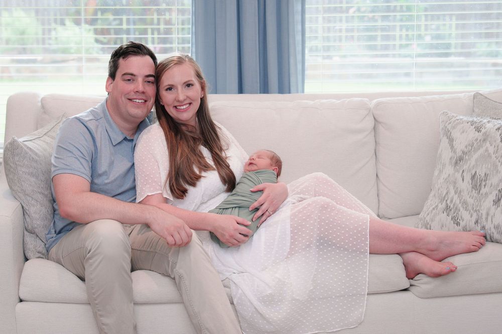 newborn photo session mom and dad holding baby boy on white couch with white dress family love bond fresh 48 Fort Worth TX  big brother