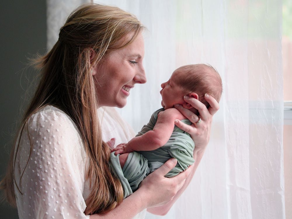 mom and newborn baby by the window natural light mom love cuddles candid posed black and white baby boy Dallas Texas big brother