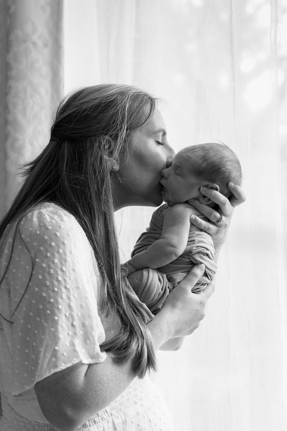 mom and newborn baby by the window natural light mom love cuddles candid posed black and white baby boy Dallas Texas big brother