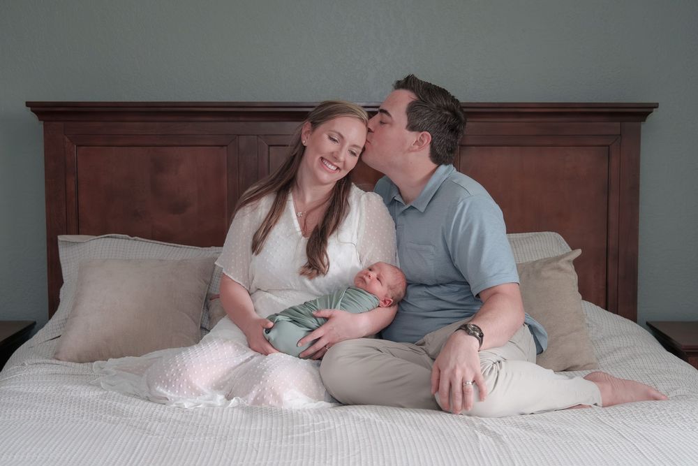mom dad on bed in home newborn baby window natural light mom love cuddles candid posed black and white baby boy Dallas Texas big brother