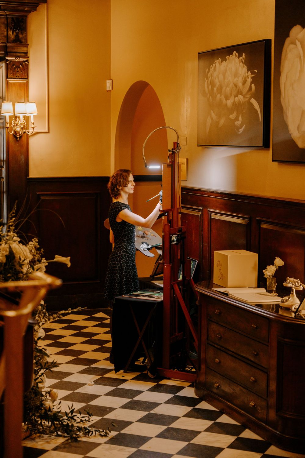 A woman plays theremin in an elegant room with checkered floors and warm amber walls.