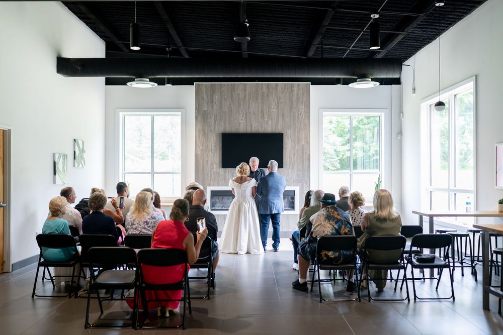 Small intimate wedding ceremony with guests seated facing couple and officiant in modern venue.