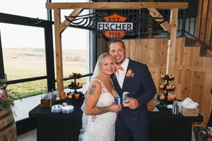 Bride and groom smiling together under Fischer Est. 2025 sign at rustic barn wedding reception.