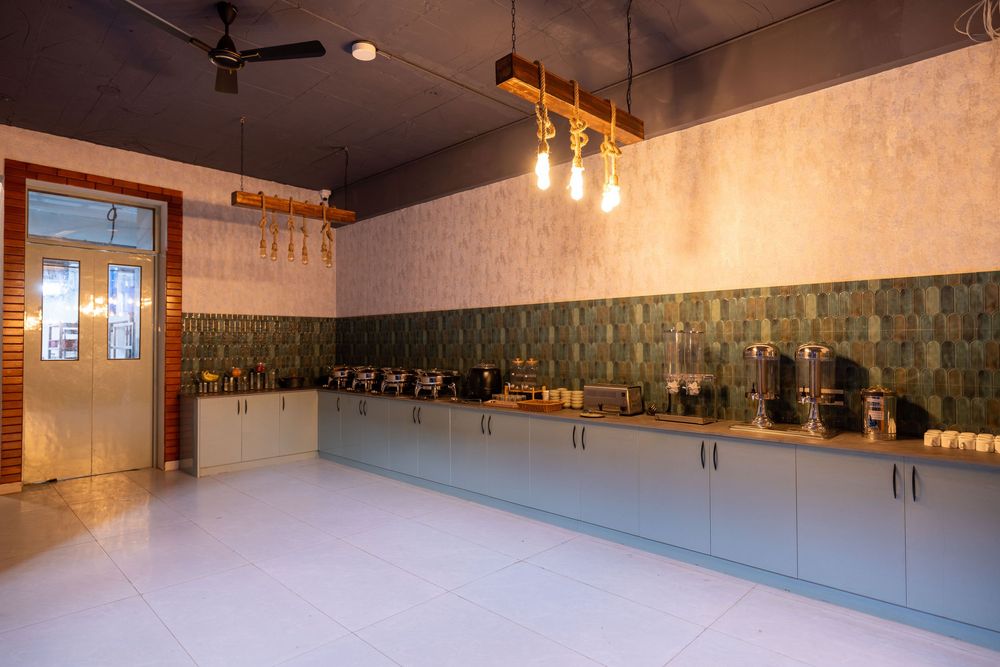 Modern kitchen space with green tile backsplash, gray cabinets, pendant lights, and white floors.