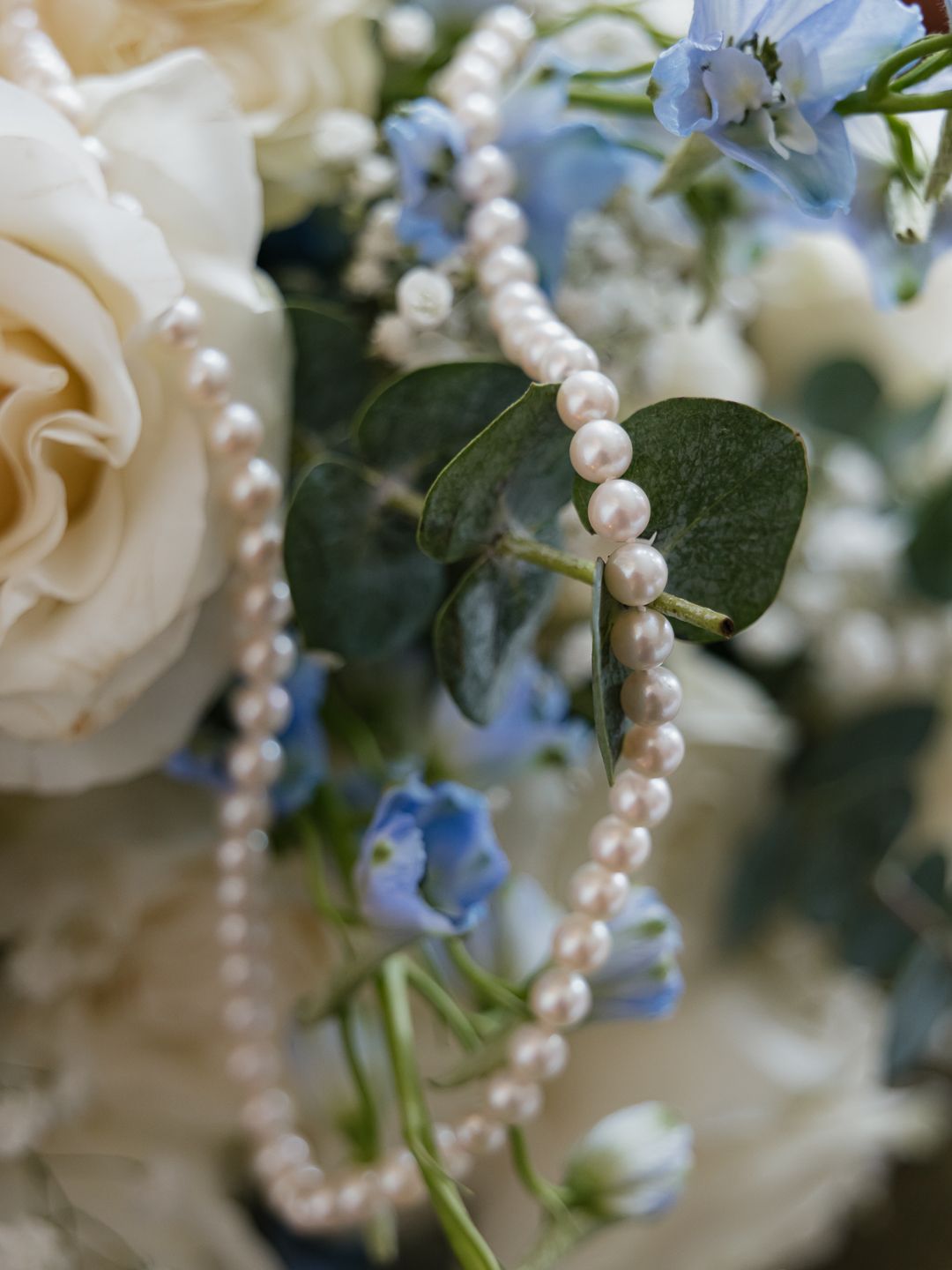 Elegant white urn vase with pink roses, white orchids, and blush blooms for a wedding ceremony outdoors.
