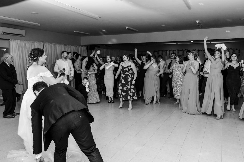 Black and white wedding reception photo showing guests gathered on dance floor as bride prepares to toss bouquet.