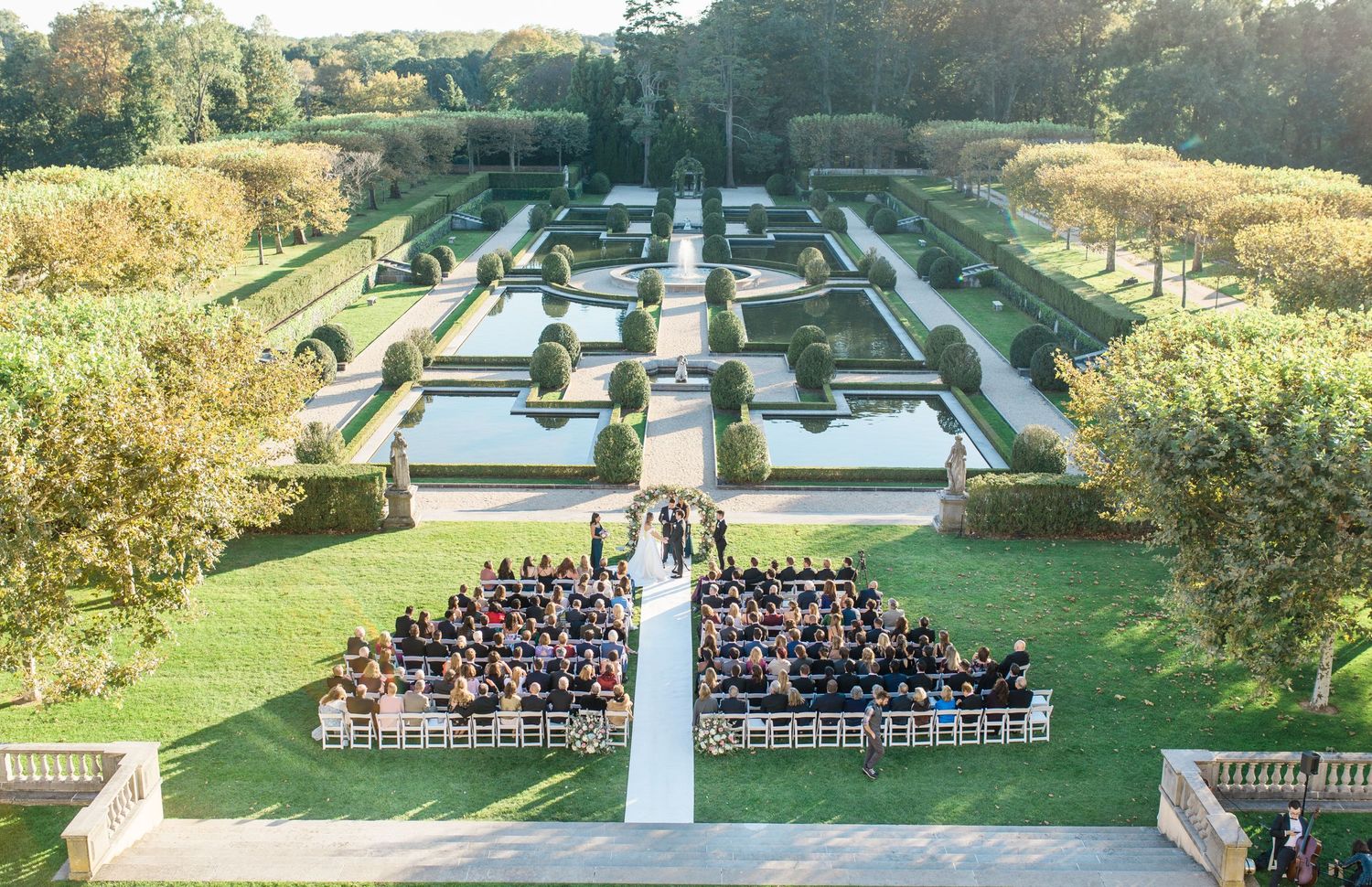 Aerial view of a formal garden wedding ceremony setup with symmetrical landscaping and guest seating.