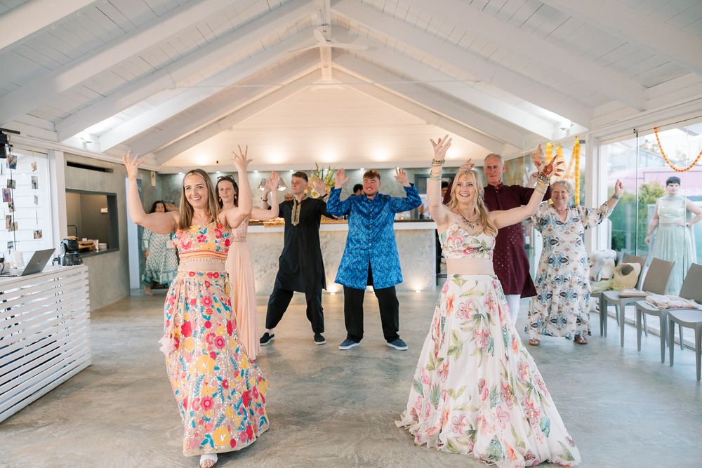 Bride and friends dancing together during the Mehndi and Sangeet celebration by the sea in Cascais, Portugal.