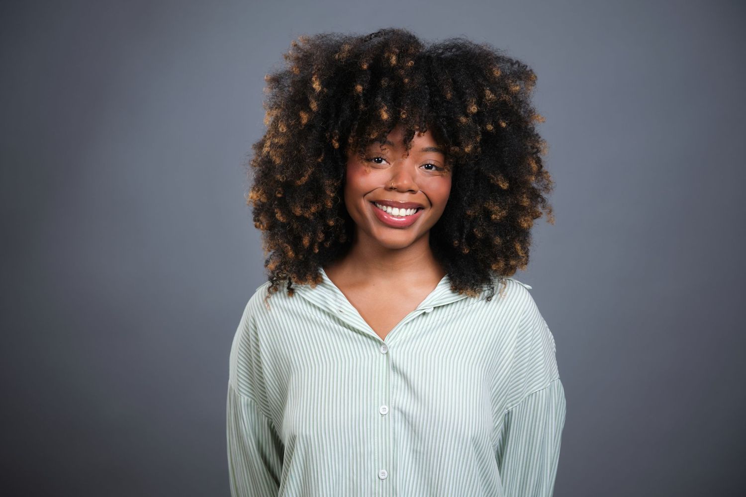 A women stands in front of a grey backdrop for a headshot during a headshot event in Appleton, Wisconsin
