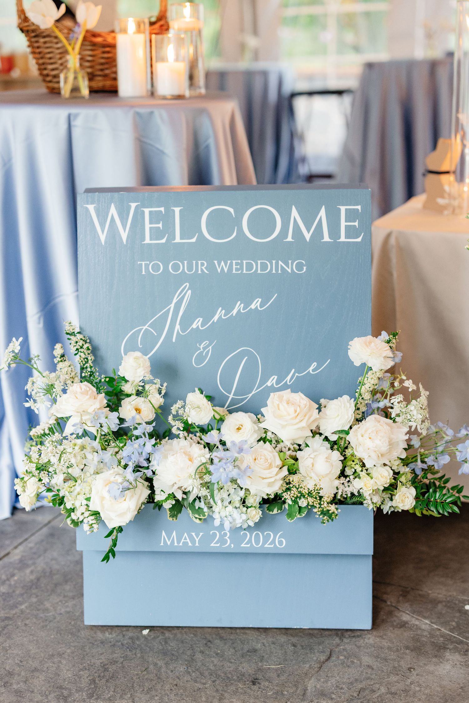 Blue wedding welcome sign for Shanna and Dave dated May 23 2026 with white floral decor.