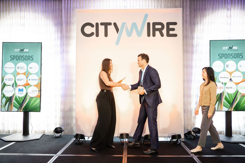Two professionals shake hands on stage at a Citywire sponsors event.