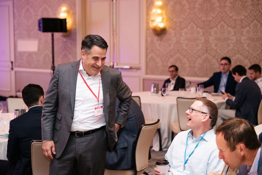 Business professionals networking and laughing at a Citywire conference event.