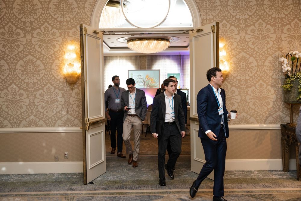 Business professionals walking through elegant ballroom doors at a corporate conference event.