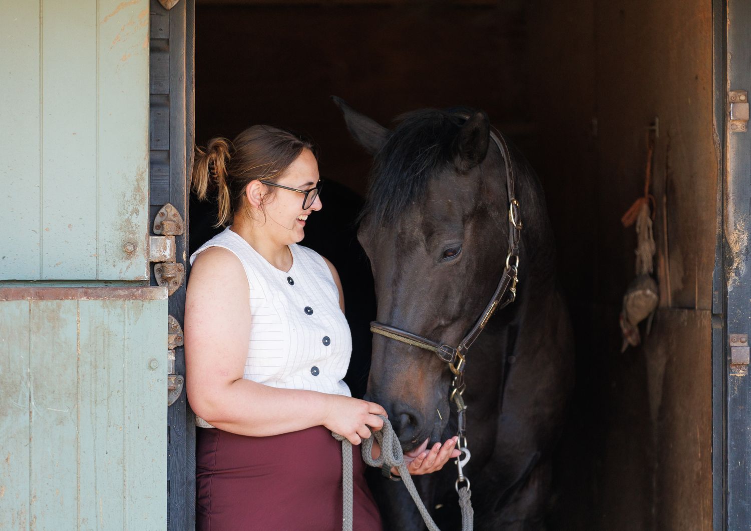 A horse and its rider enjoy an outdoor photoshoot session near rustic wooden fencing on a sunny day.