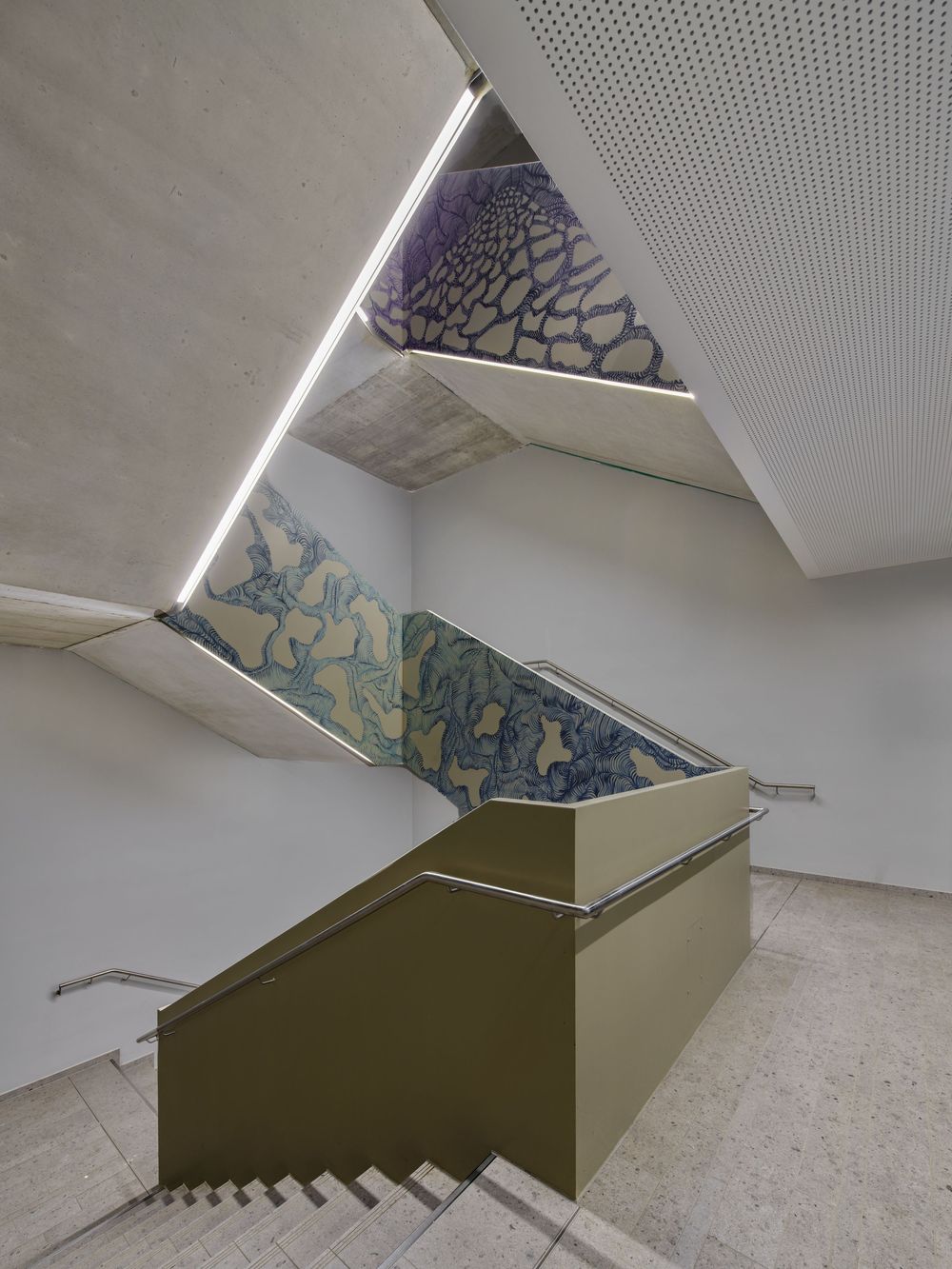Modern concrete stairwell with olive green railing wall, angular ceiling, linear skylight and a blue organic patterned mural.