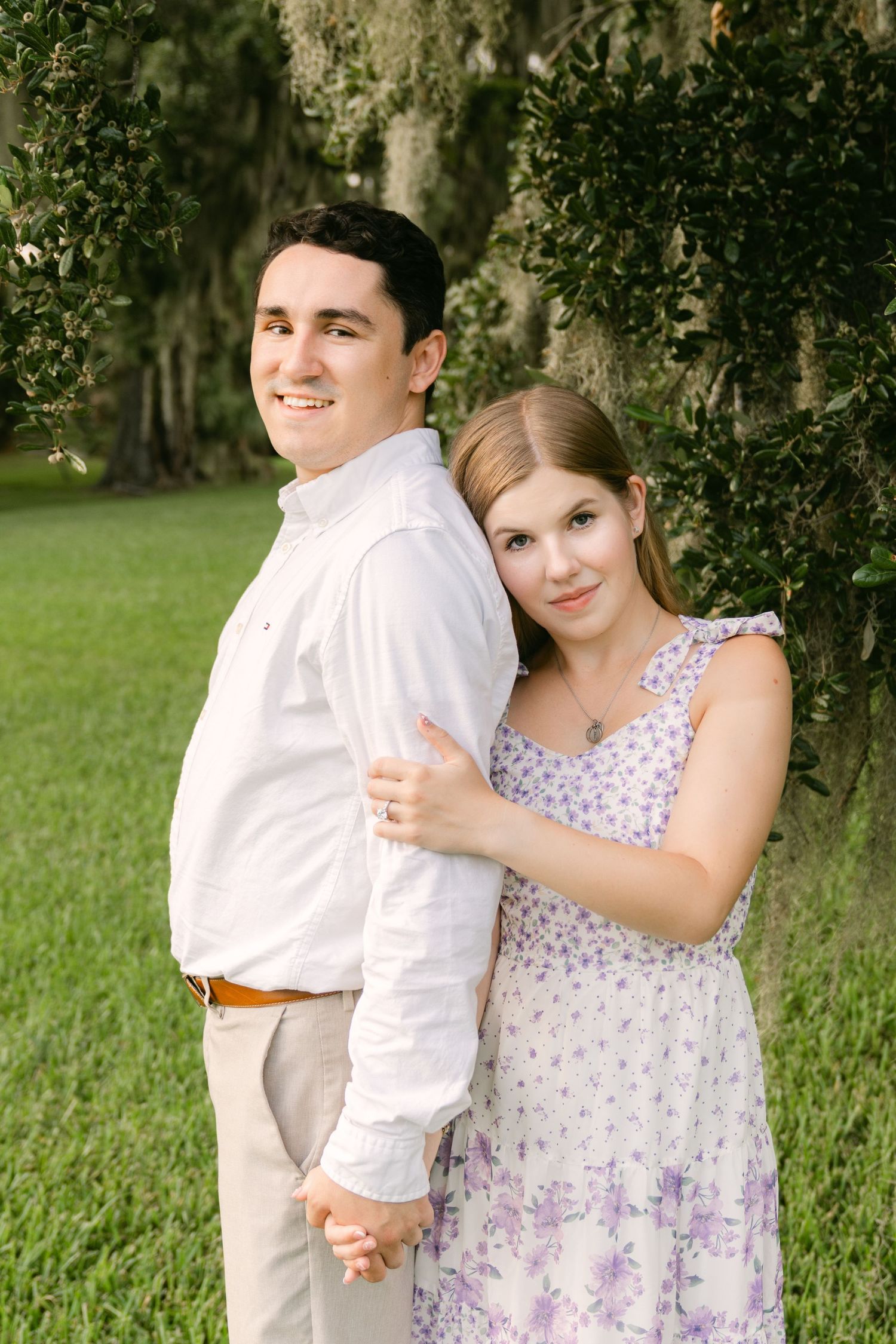 Engaged couple snuggling beneath Spanish moss-covered trees during a Jekyll Island engagement portrait session with Lindy Rebro Photography