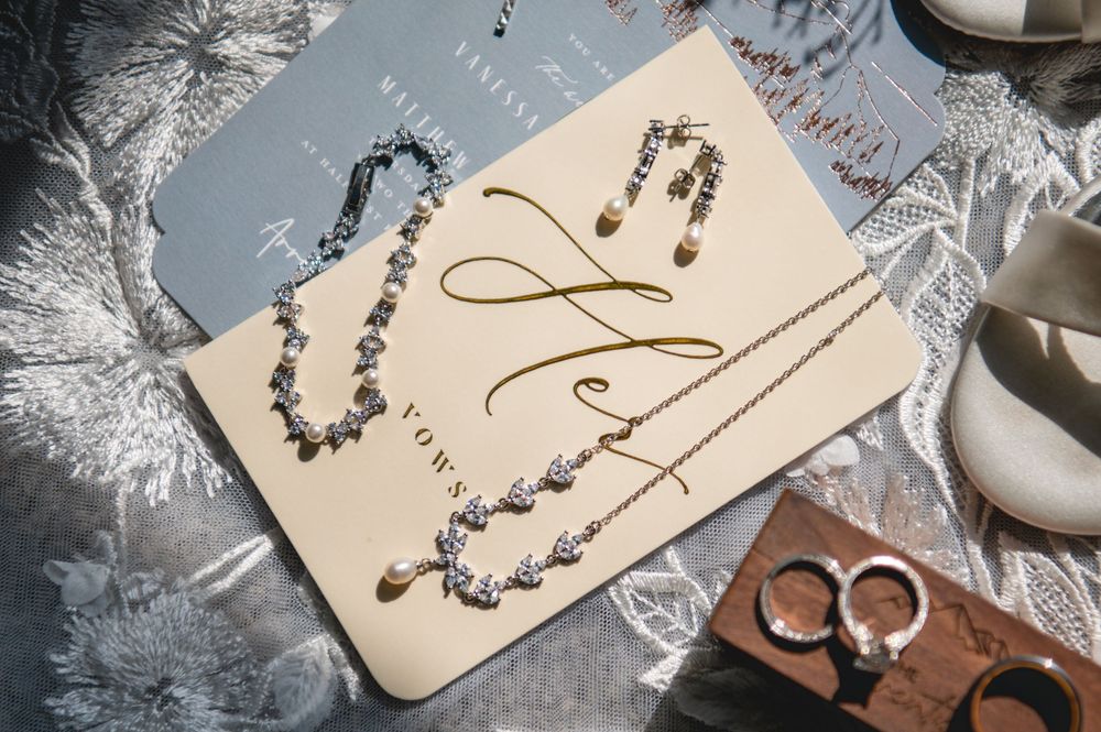 Elegant bridal jewelry flatlay featuring a crystal necklace, earrings, and rings displayed on a vow card.