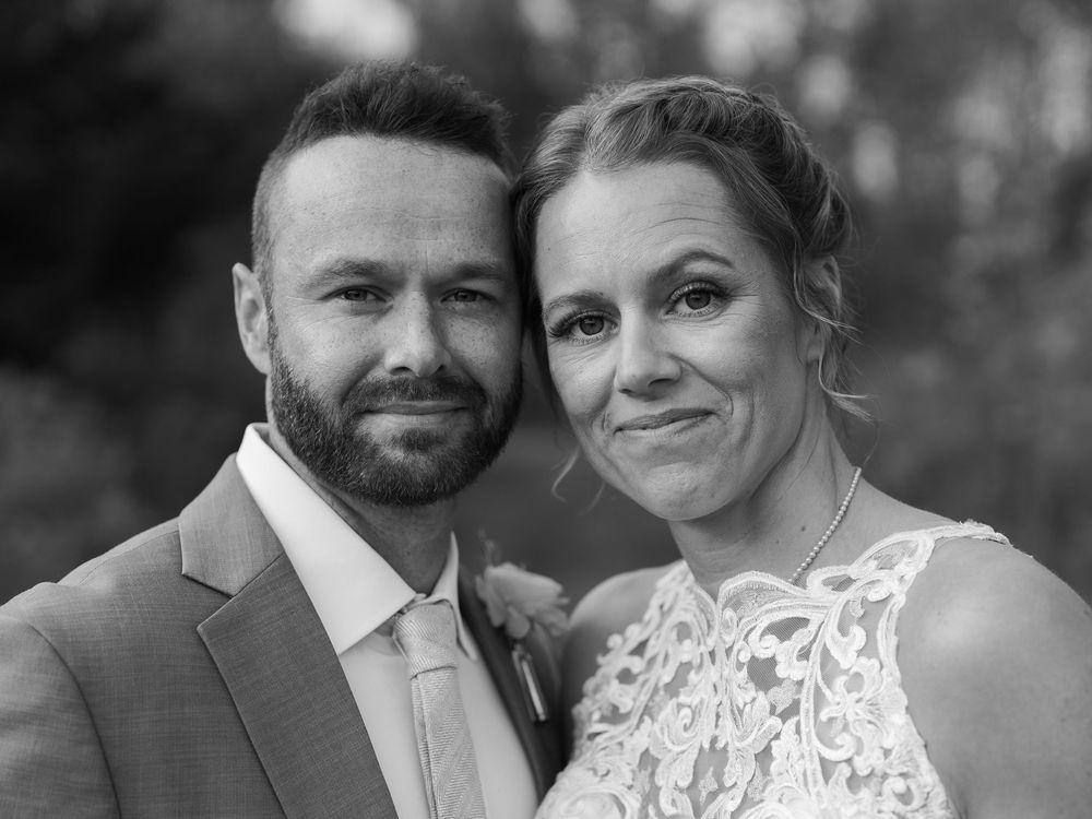 Black and white wedding portrait of smiling bride and groom posing together outdoors.