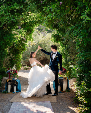 Bride and groom dancing under a lush green garden arch on their wedding day, surrounded by elegant decor.