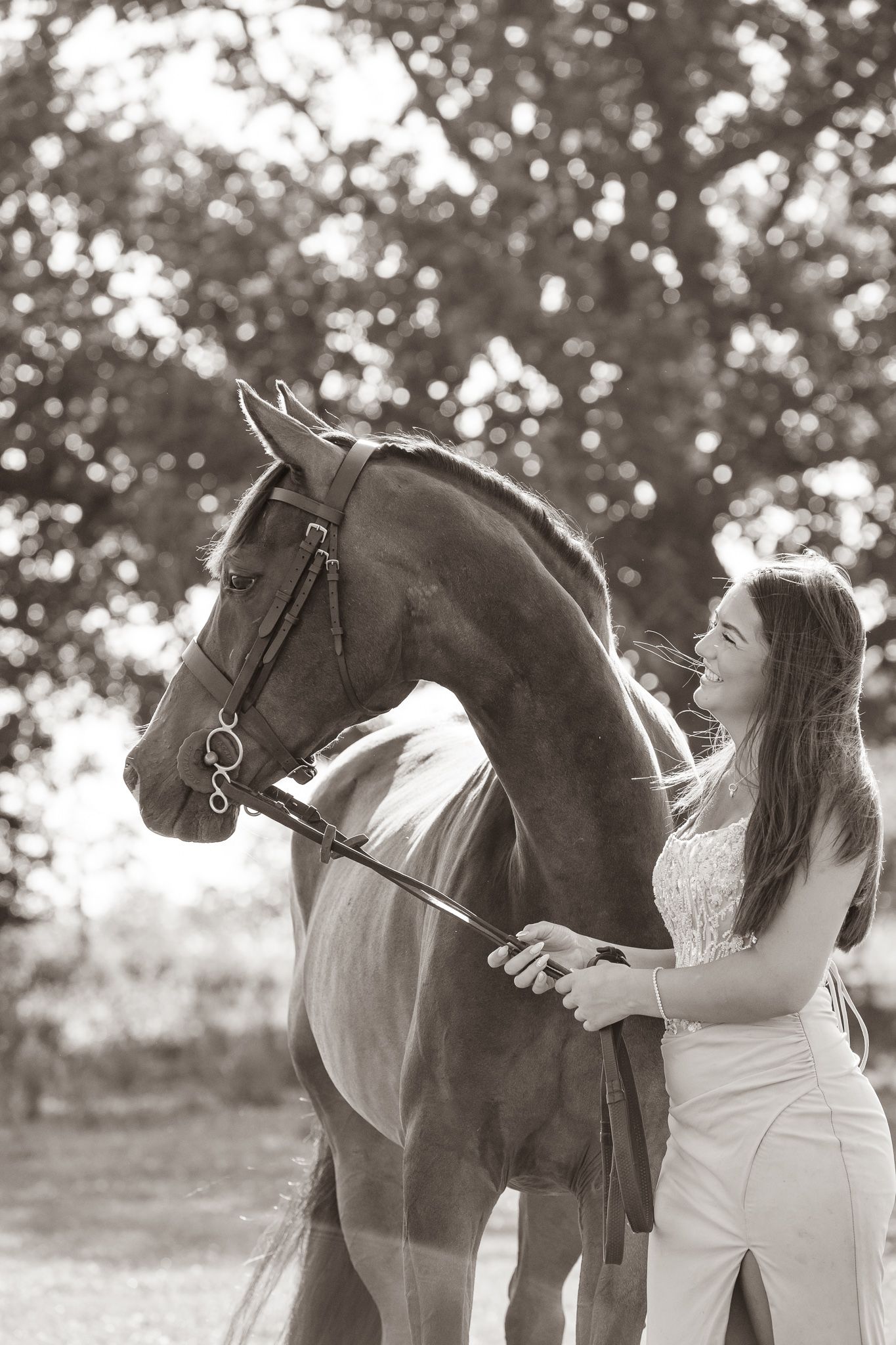 A smiling couple stands with a black and white horse and small dog in front of a white van on a farm.